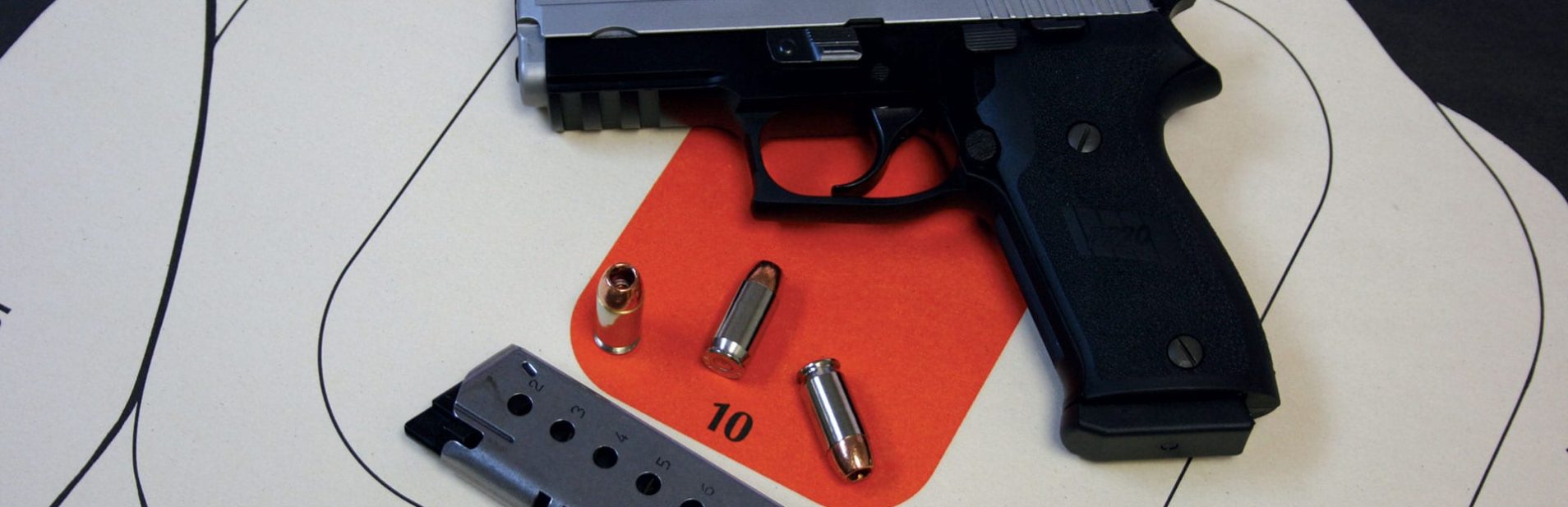 Pistol Training 2 PIstol and bullets laying on a target.